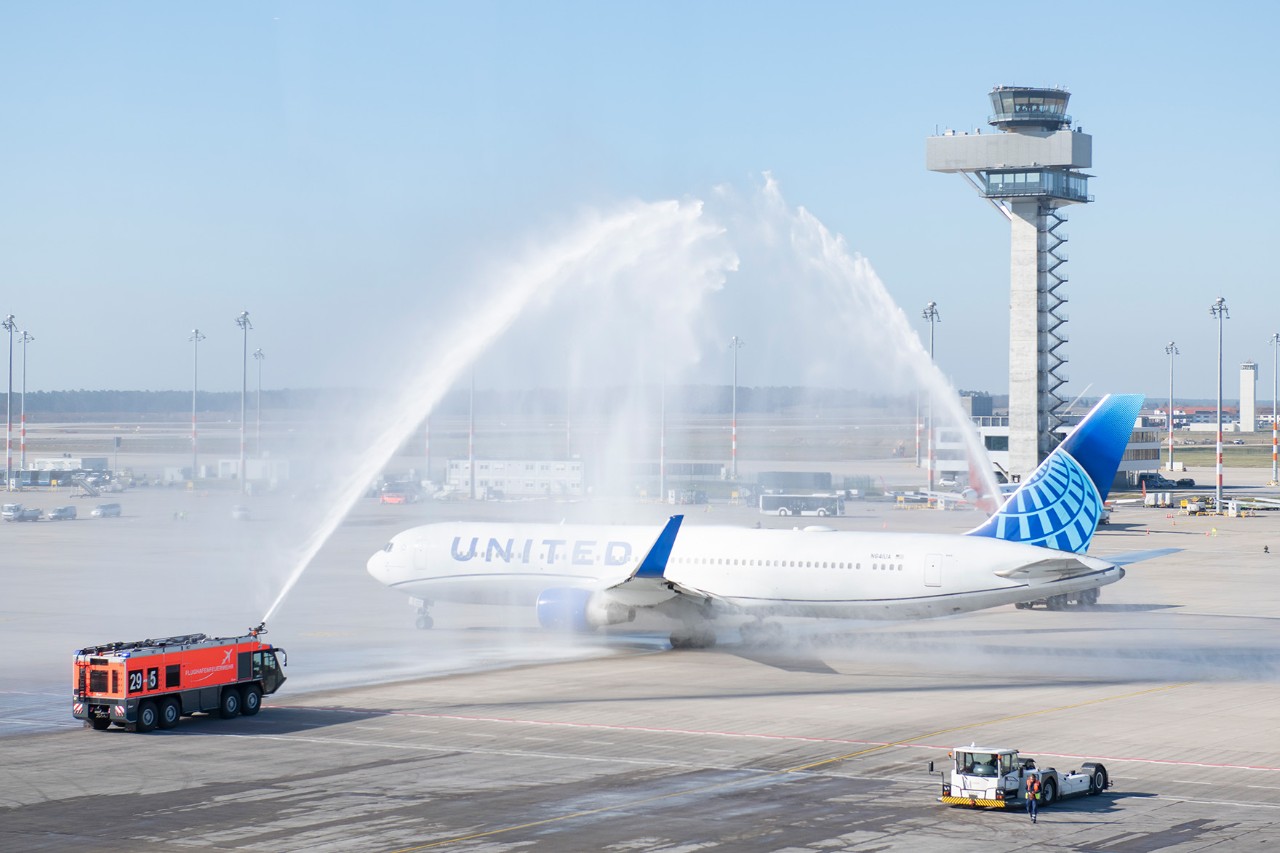 United Airlines aircraft on the apron with airport fire brigade and water fountain