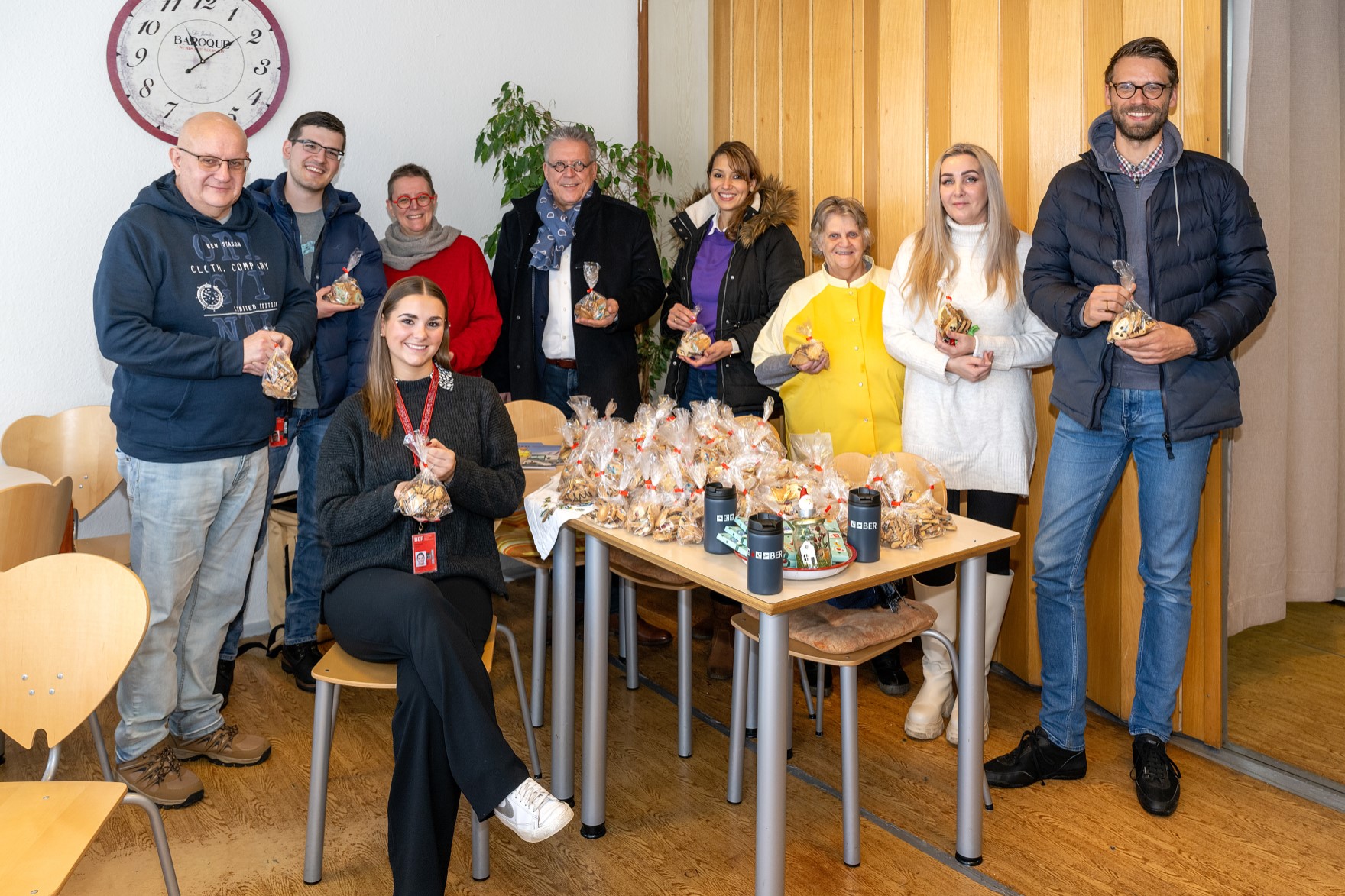 Eine Gruppe von Personen mit Plätzchen in den Händen lächeln in die Kamera.