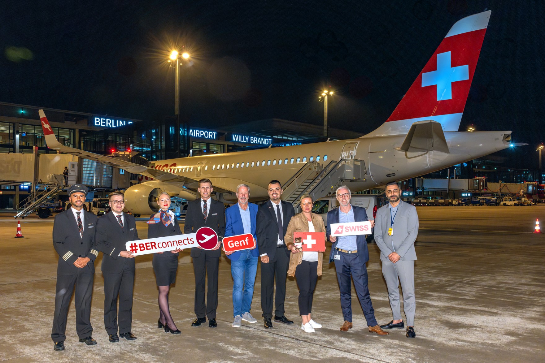 Eine Gruppe von Personen posiert mit Schildern auf dem Vorfeld vor einem Flugzeug.