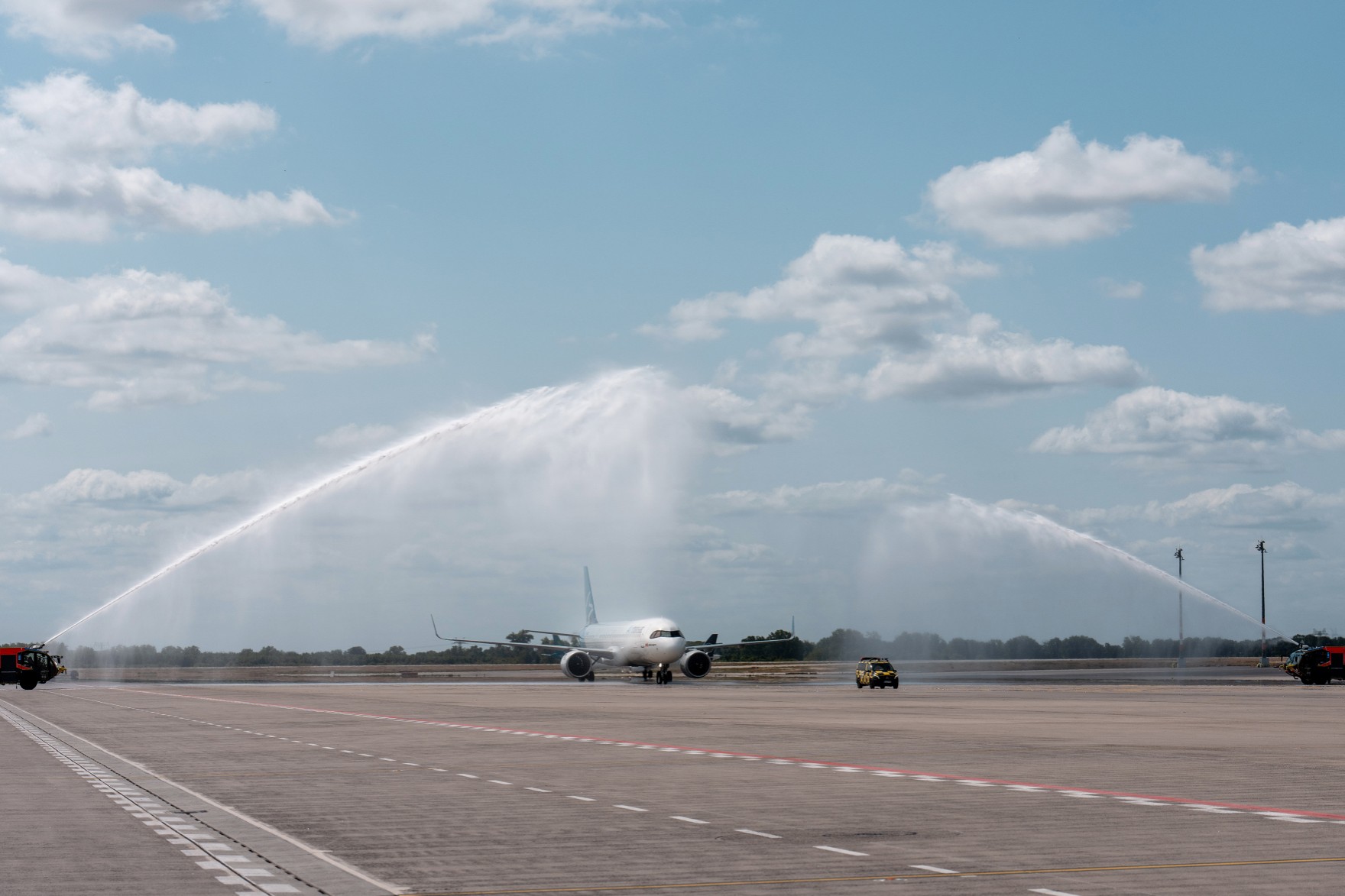 Ein Flugzeug der Airline Air Transat rollt auf dem Vorfeld, Wasserfontänen über dem Flugzeug sind zu sehen / A plane belonging to the airline Air Transat is taxiing on the apron, with water fountains arching over the aircraft.