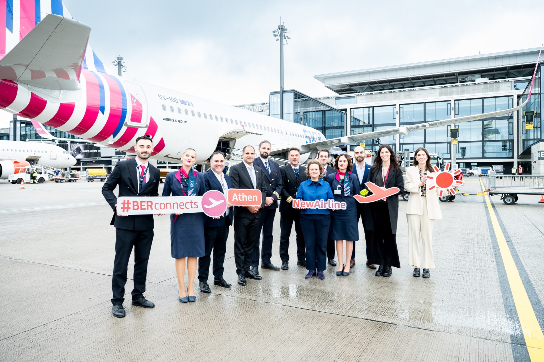 Eine Gruppe von Personen posiert mit Schildern auf dem Vorfeld vor einem Flugzeug.