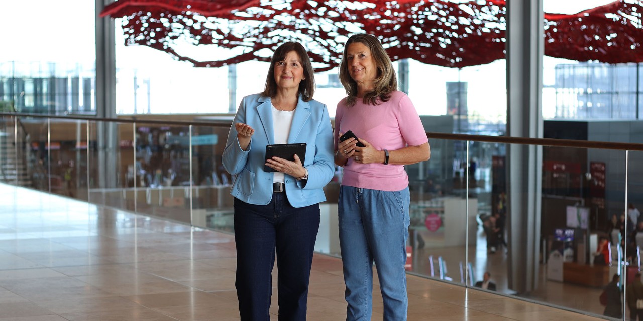Zwei Frauen stehen im Terminal und besprechen sich zusammen.