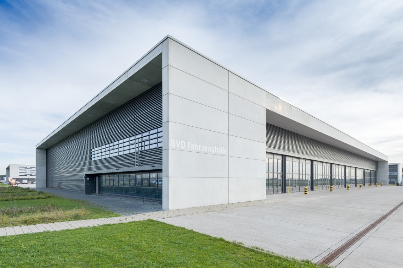 modernes Gebäude mit Beton und Glas. Davor eine Freifläche