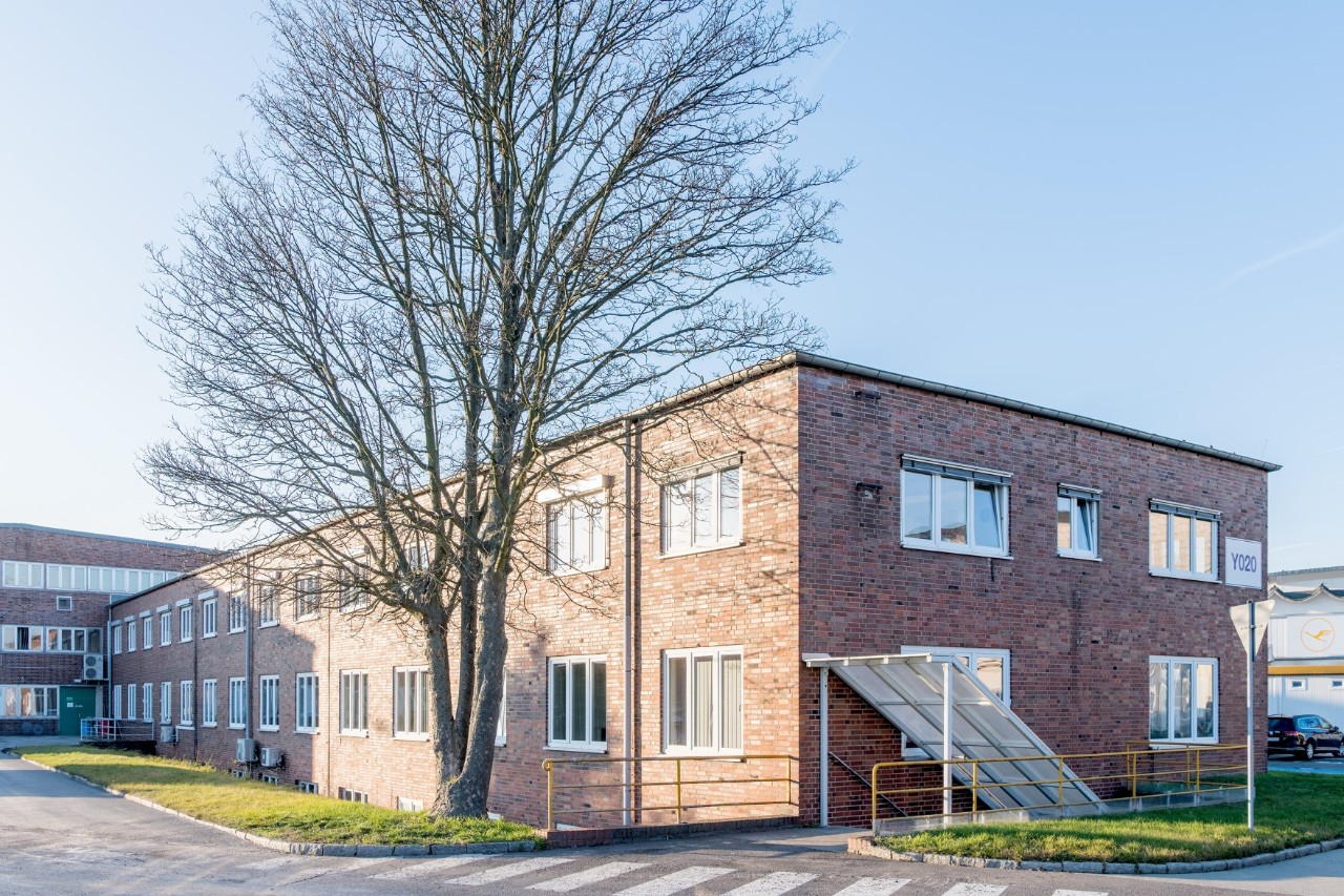 Ein altes Gebäude aus Backstein. Davor eine Straße.