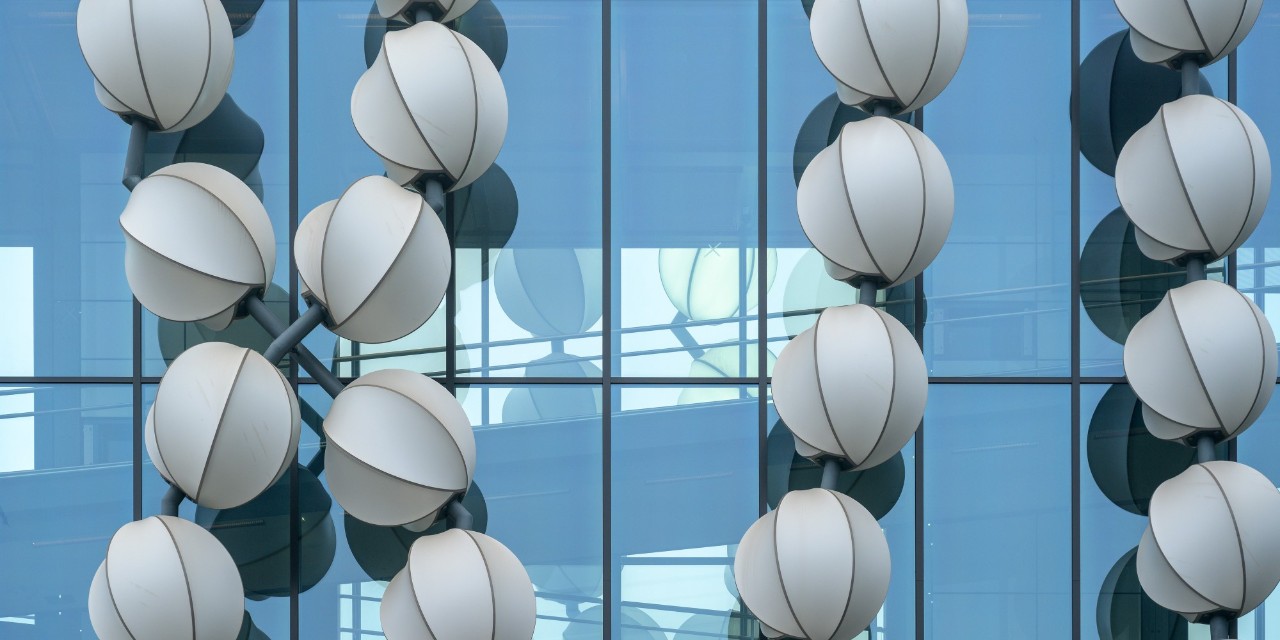Eine Kunstinstallation in Form einer riesigen Perlenkette aus Lampions windet sich um eine gläserne Fluggastbrücke.