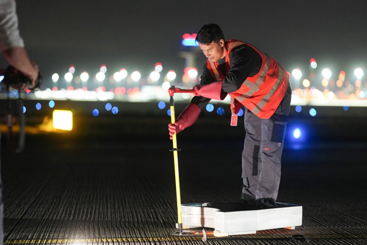 Ein Mitarbeitender der Flughafengesellschaft tauscht auf dem Vorfeld ein herkömmliches Feuer gegen ein LED-Feuer aus.