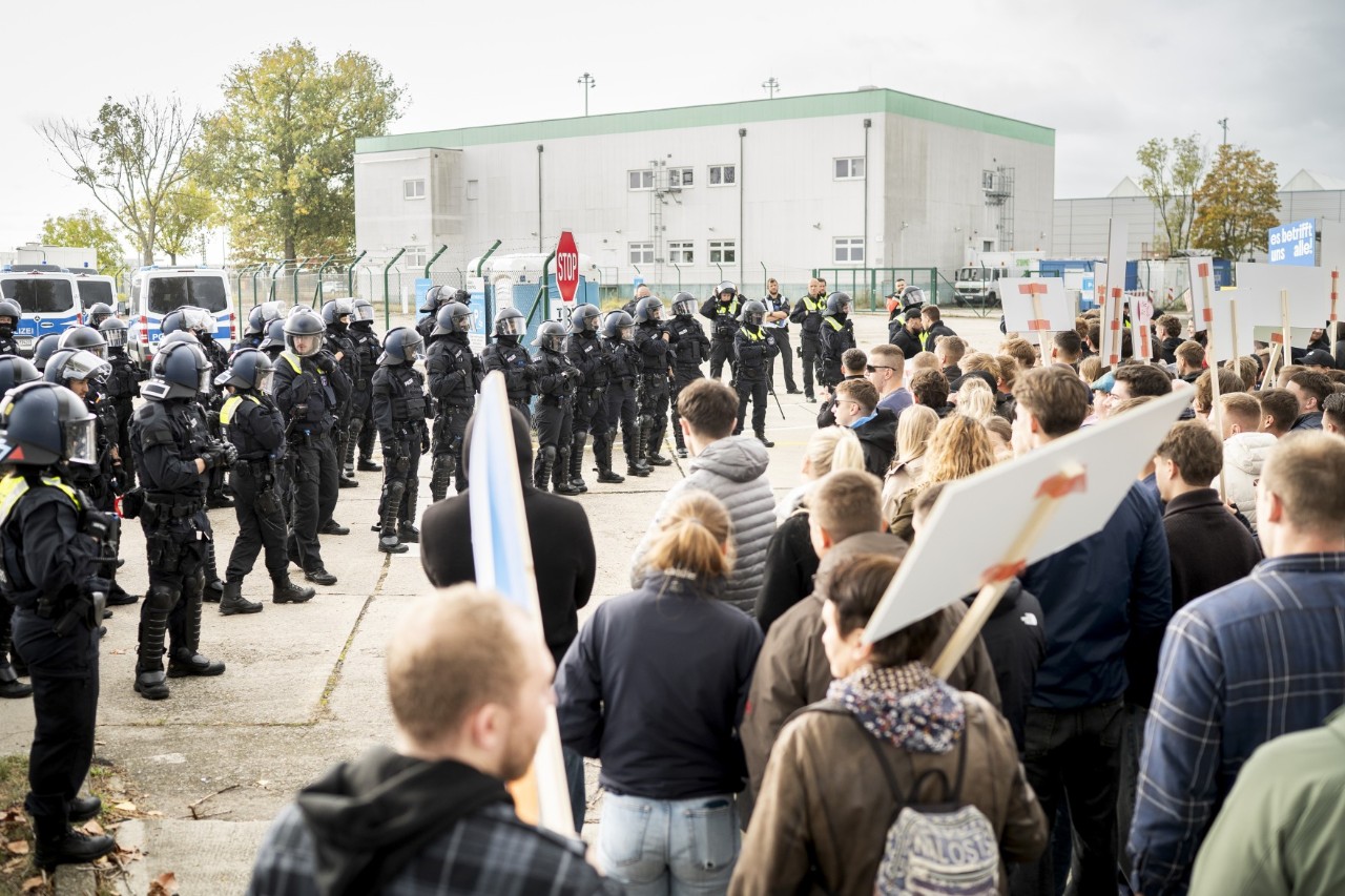 Eine Gruppe von Menschen mit Schildern steht einer Reihe von Polizisten gegenüber