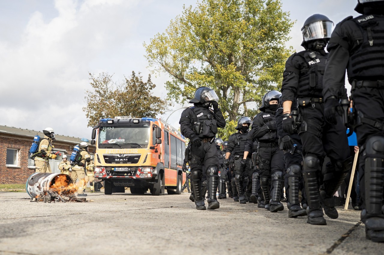 Eine umgestürzte Feuertonne, Feuerwehrleute, Polizisten und ein Feuerwehr-Fahrzeug