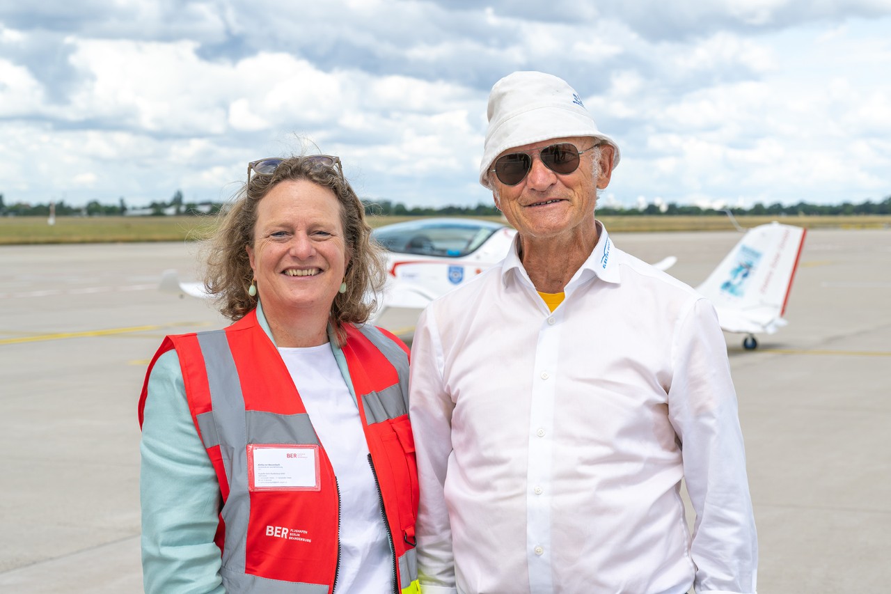 Ein Mann und eine Frau stehen Arm in Arm vor einem E-Flugzeug