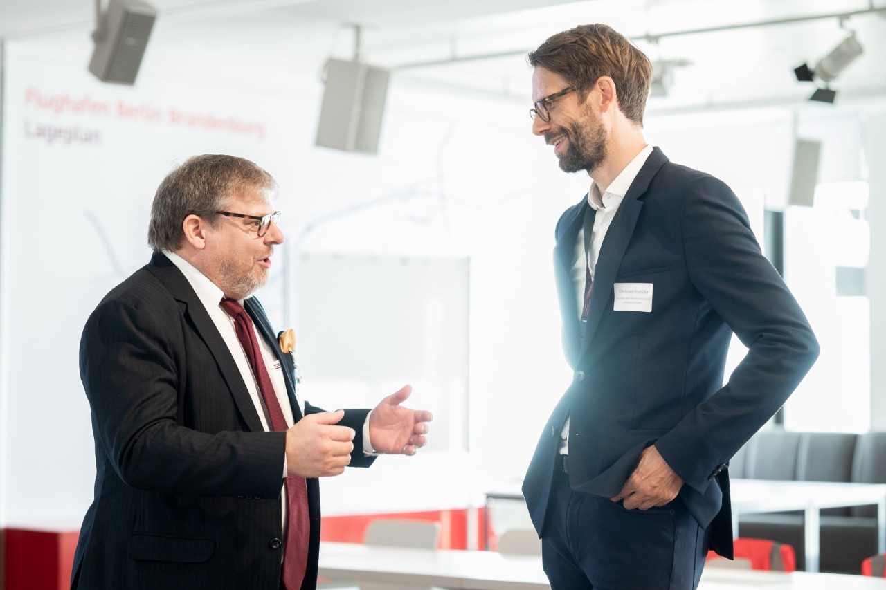 Zwei Herren in Anzügen unterhalten sich angeregt.