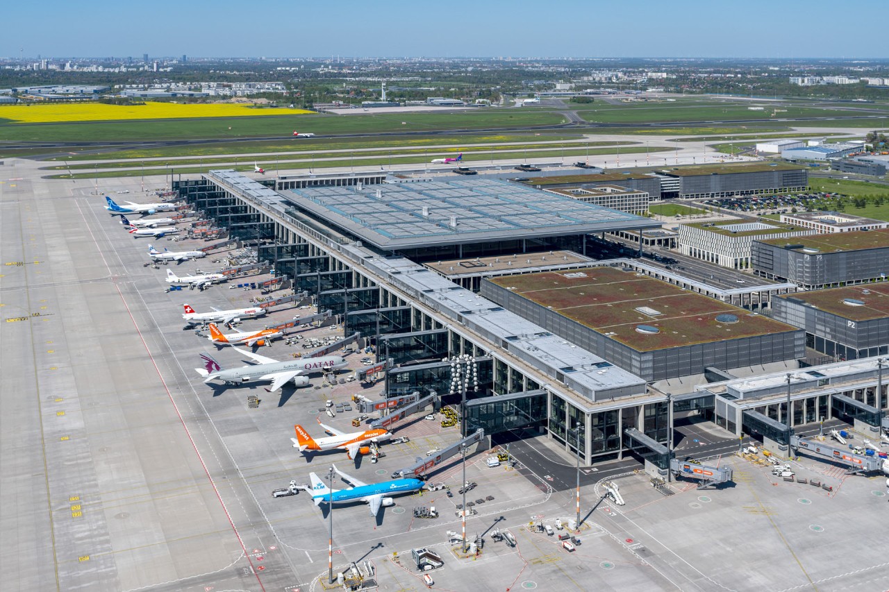 Luftbildes des Flughafens BER. Im Bild das Terminal 1, davor zahlreiche Flugzeuge auf dem Vorfeld.