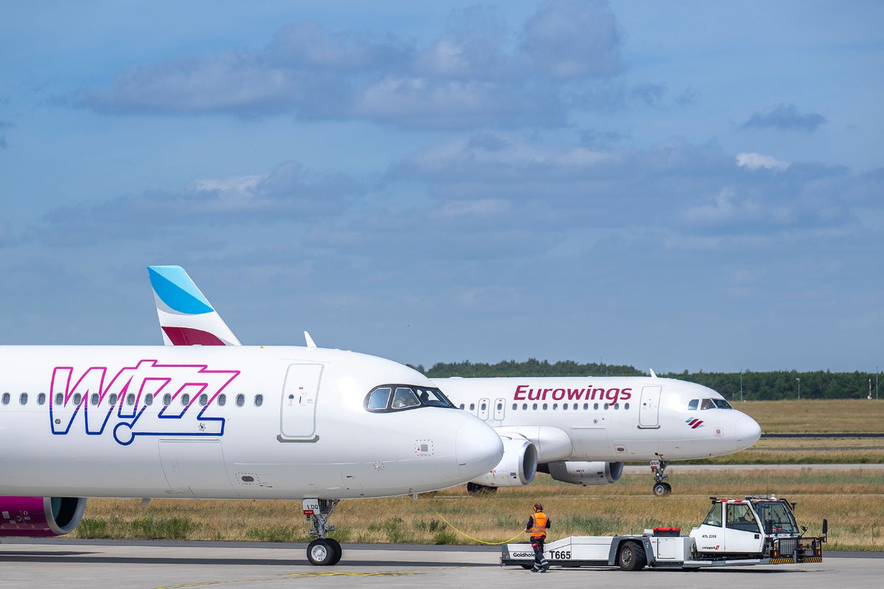 Ein Flugzeug der Airline Wizz Air und ein Flugzeug der Airline Eurowings rollen am BER.