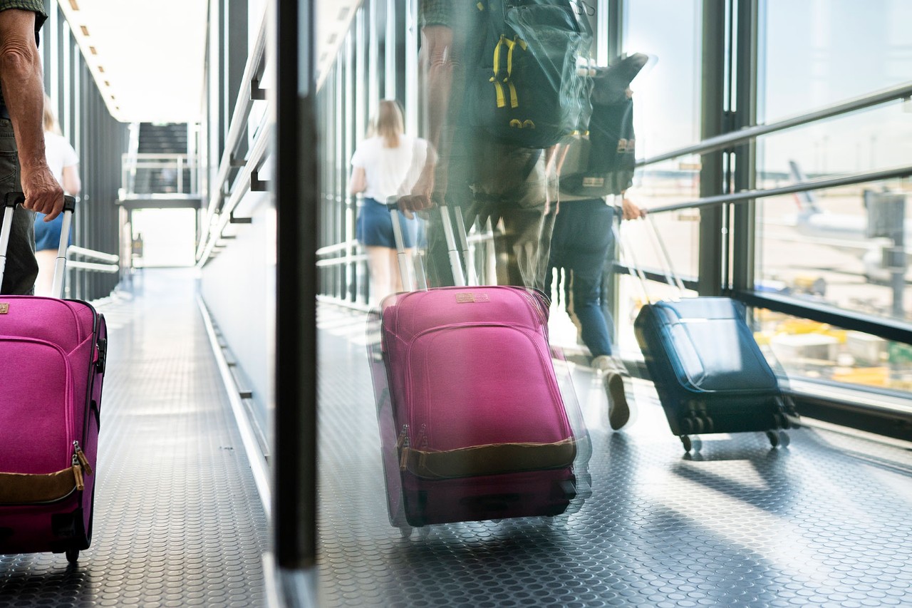 Im verspiegelten Fenster sieht man rollende Koffer am BER.