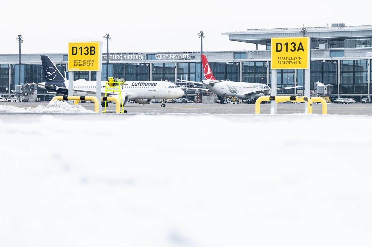 Flugzeuge steht auf dem winterlichen Vorfeld. Im Hintergrund steht das Terminal.