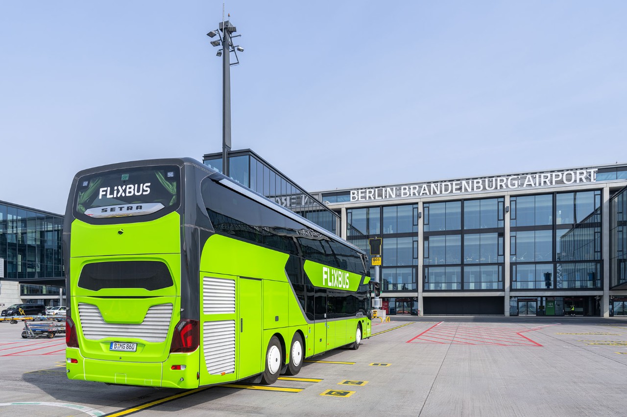 Ein grüner Fernbus steht vor dem Terminal. Der Fernbus ist von hinten zu sehen.