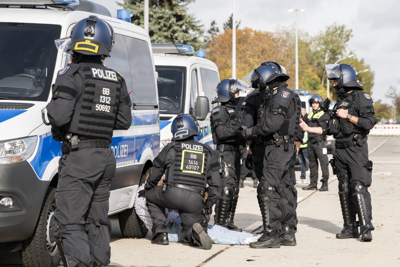 Eine Gruppe von Polizisten steht neben einer Reihe von Einsatzwagen