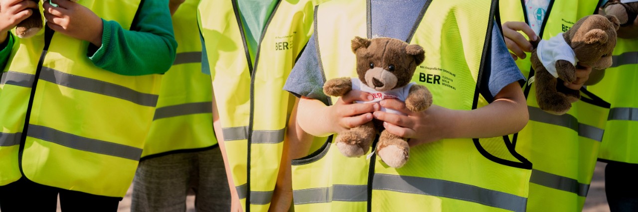 Detailaufnahme von Kindern, die gelbe Warnwesten tragen und Teddybären in den Händen halten