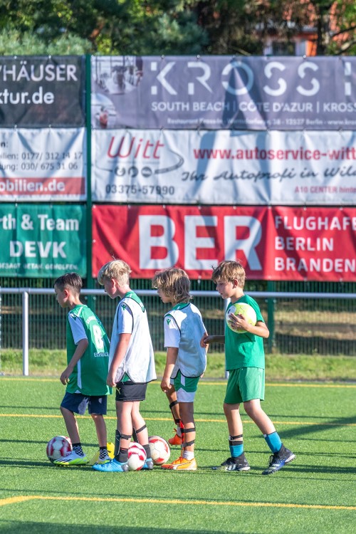 Kids playing football with red BER banner in the background © Günter Wicker / FBB