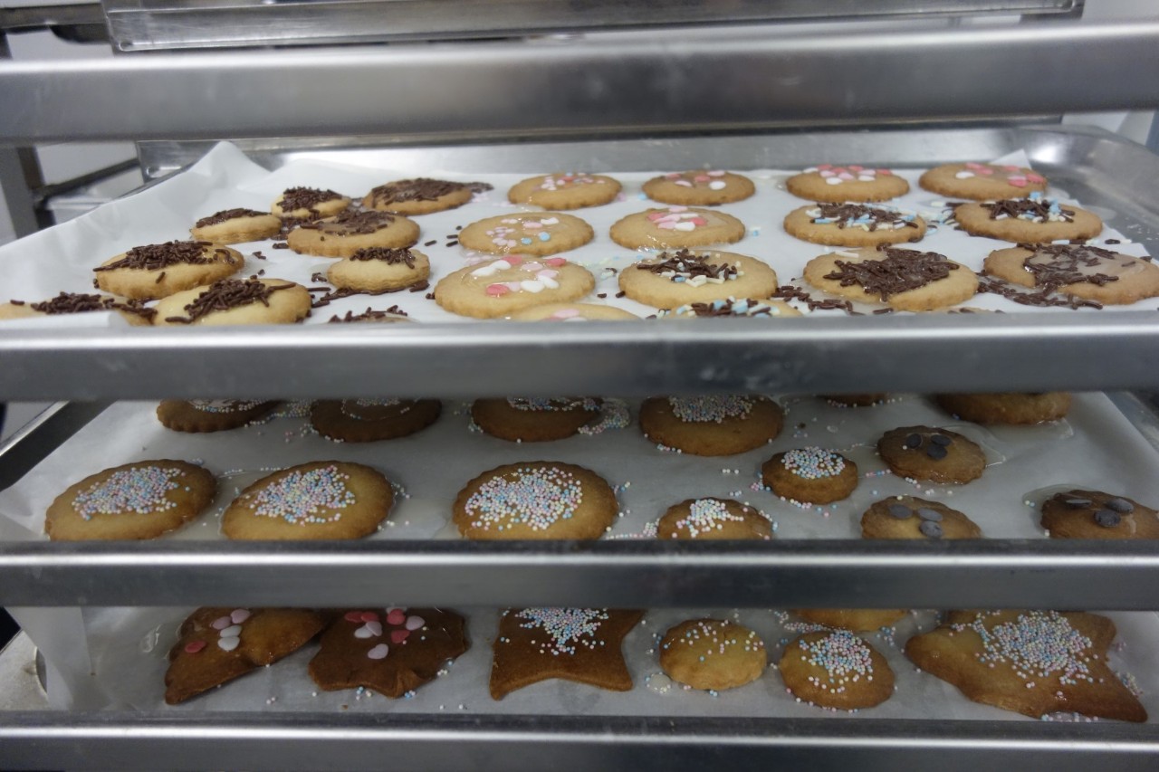 Decorated cookies are placed on baking trays to dry.