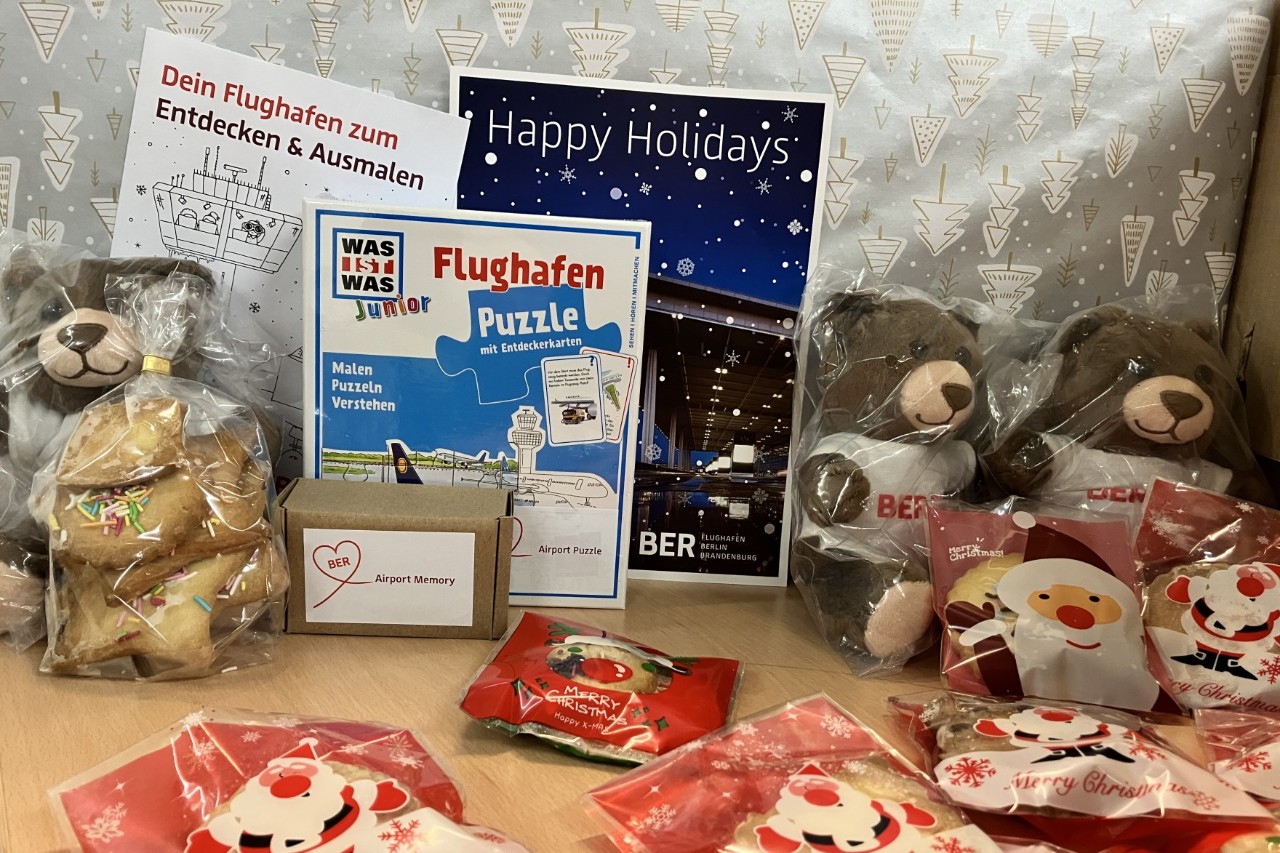 Christmas donations are set out on a table, including teddy bears, cookies and books.