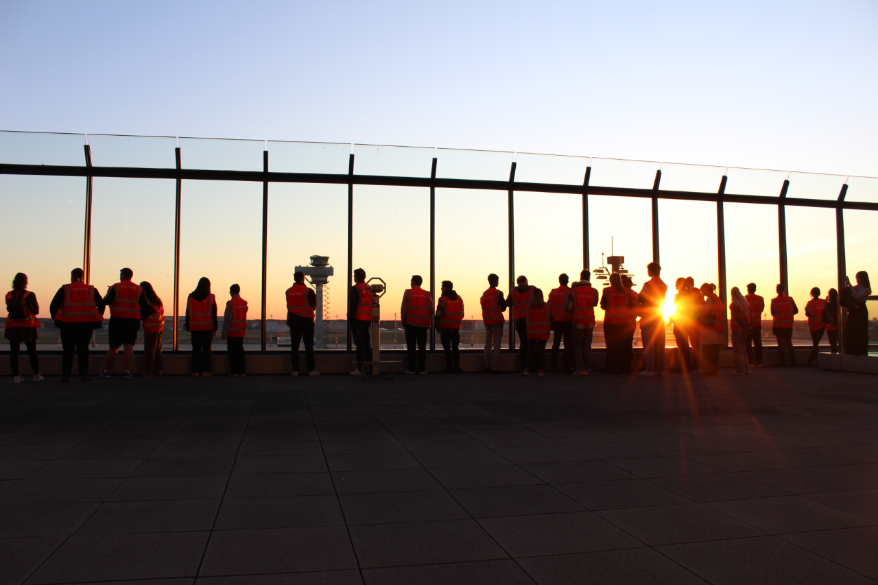 Dark silhouettes of a group of people on a terrace at sunset