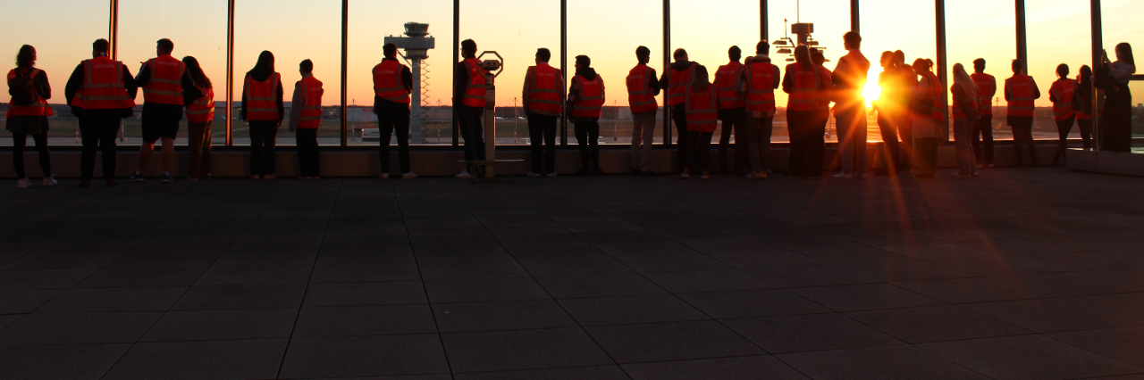 Dark silhouettes of a group of people on a terrace at sunset