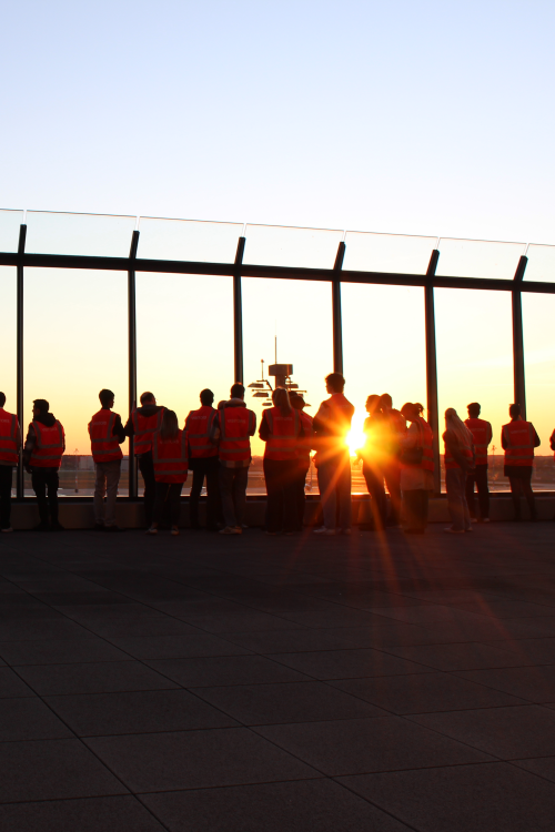 Dark silhouettes of a group of people on a terrace at sunset