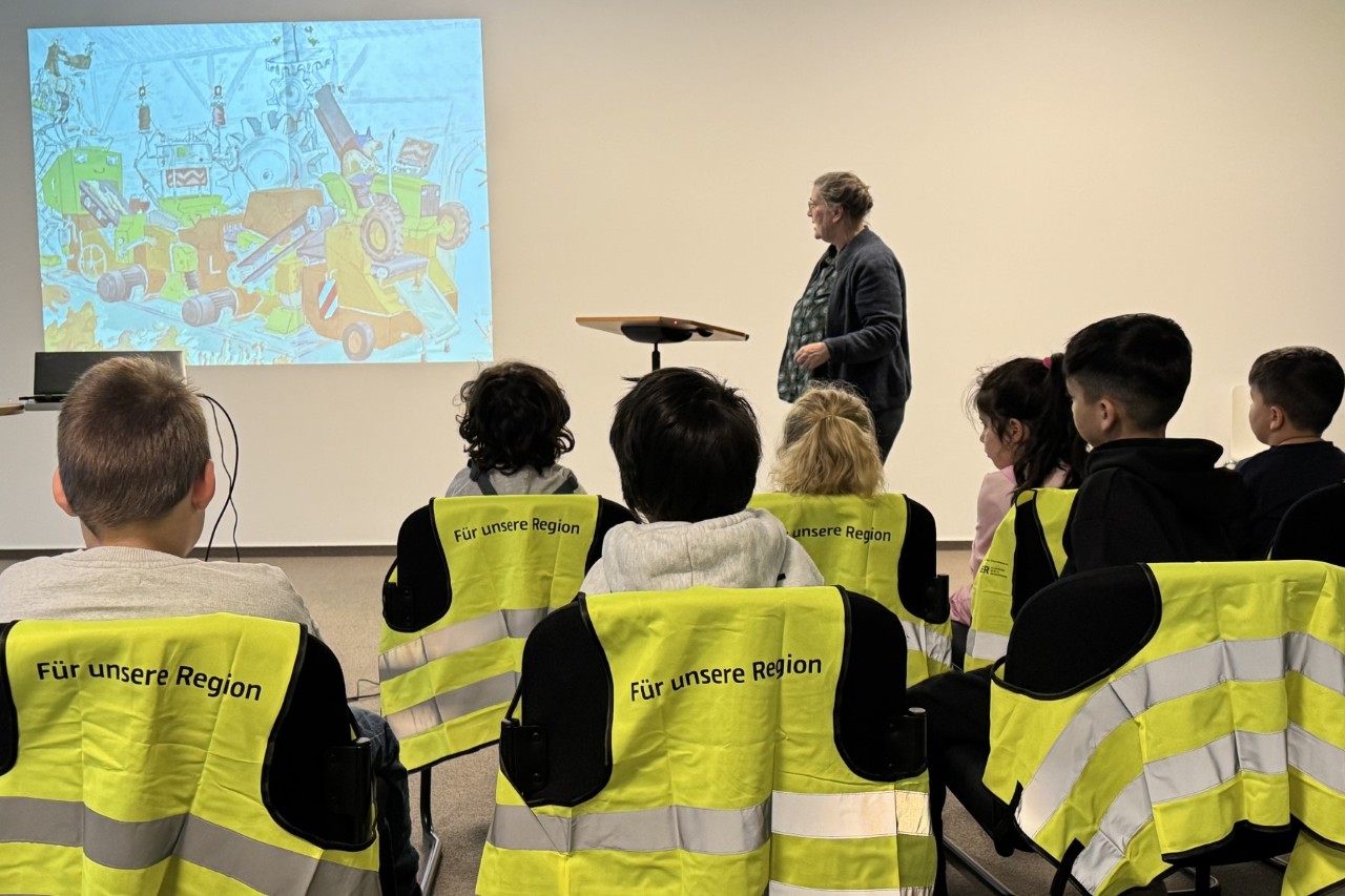 A group of children are sitting in an event room.
