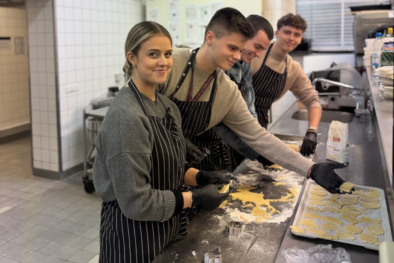 Four people look into the camera while baking biscuits.
