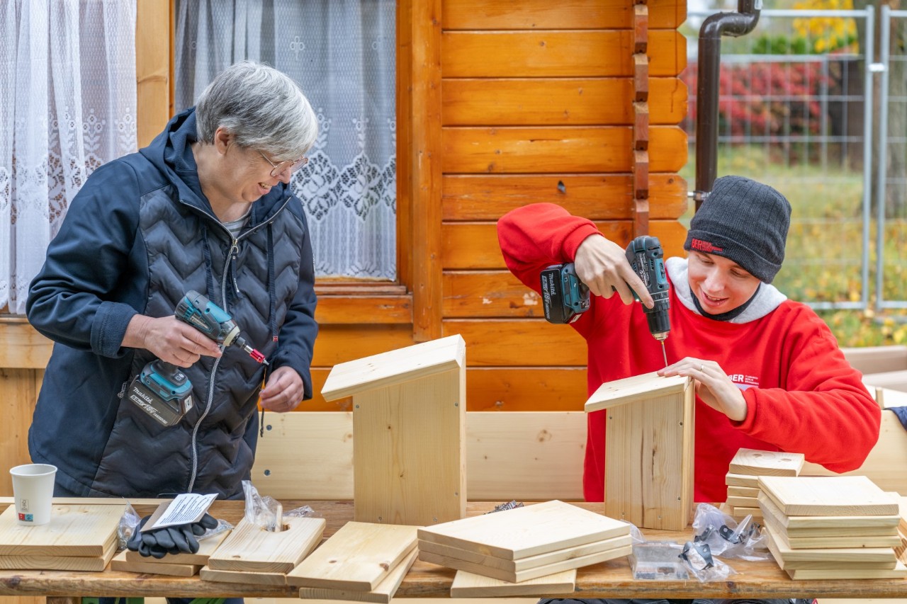 Two people are assembling wooden components.