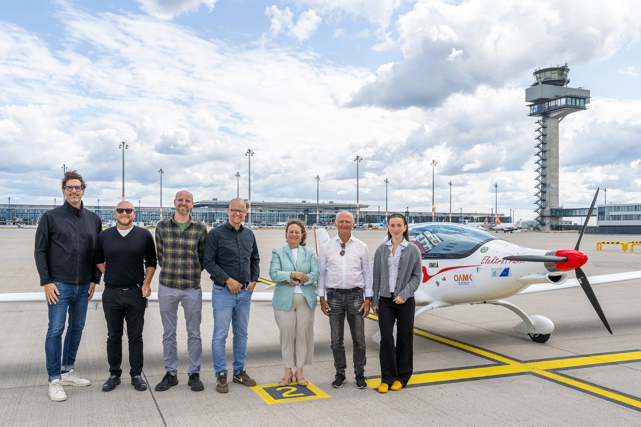 A group of people is standing in front of an electric airplane