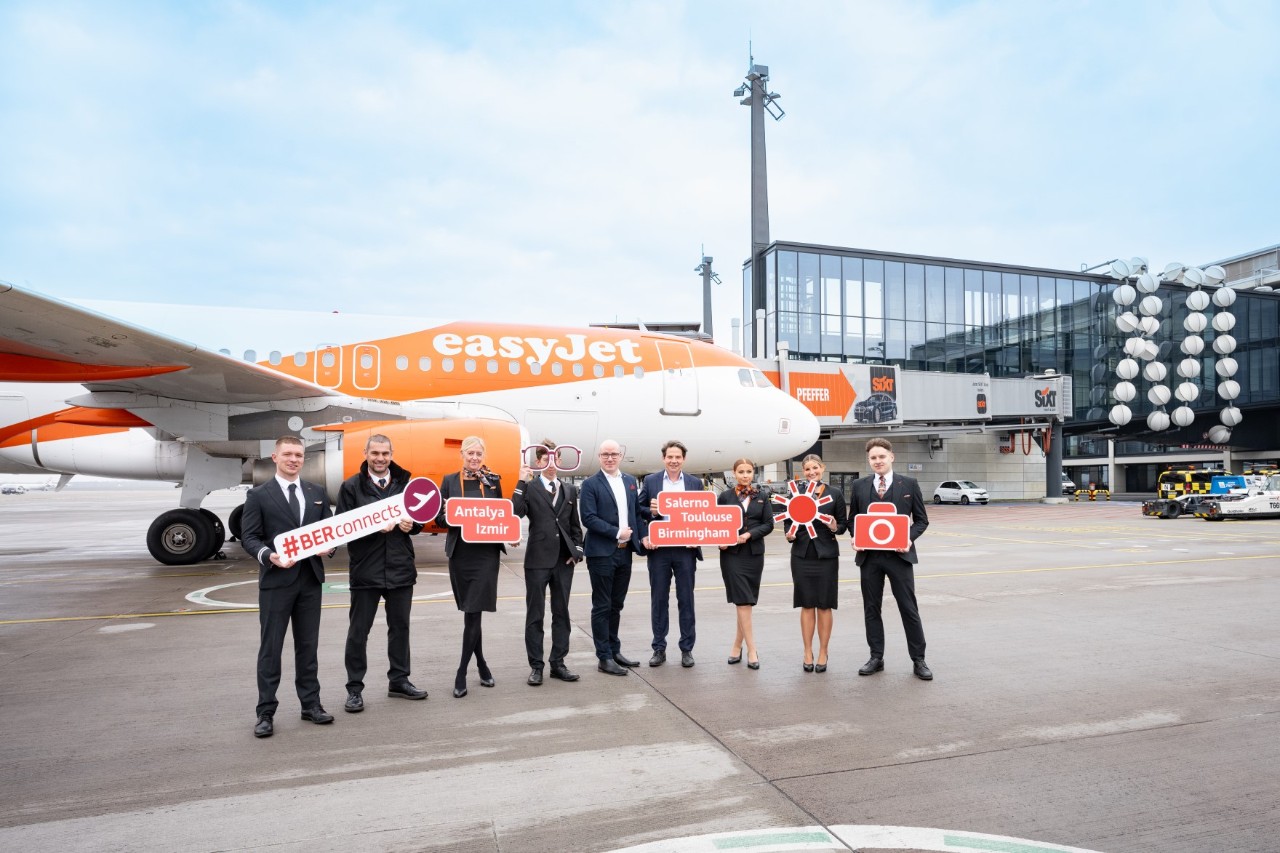 9 people hold up signs to mark the new destinations. Behind them is an easyJet aircraft.