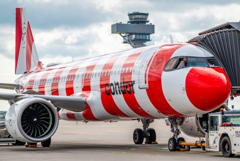 Red and white striped airplane at bridge. Behind it, the tower.