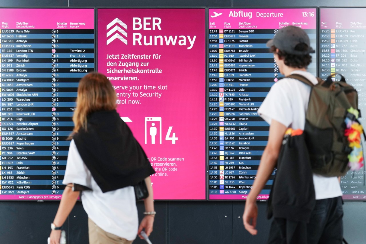 Two people standing behind a display board with ‘BER Runway’ written at the top.