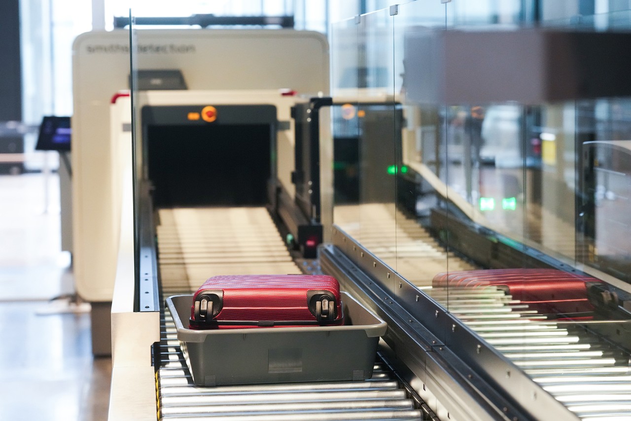 A red suitcase is lying on the baggage carousel. 