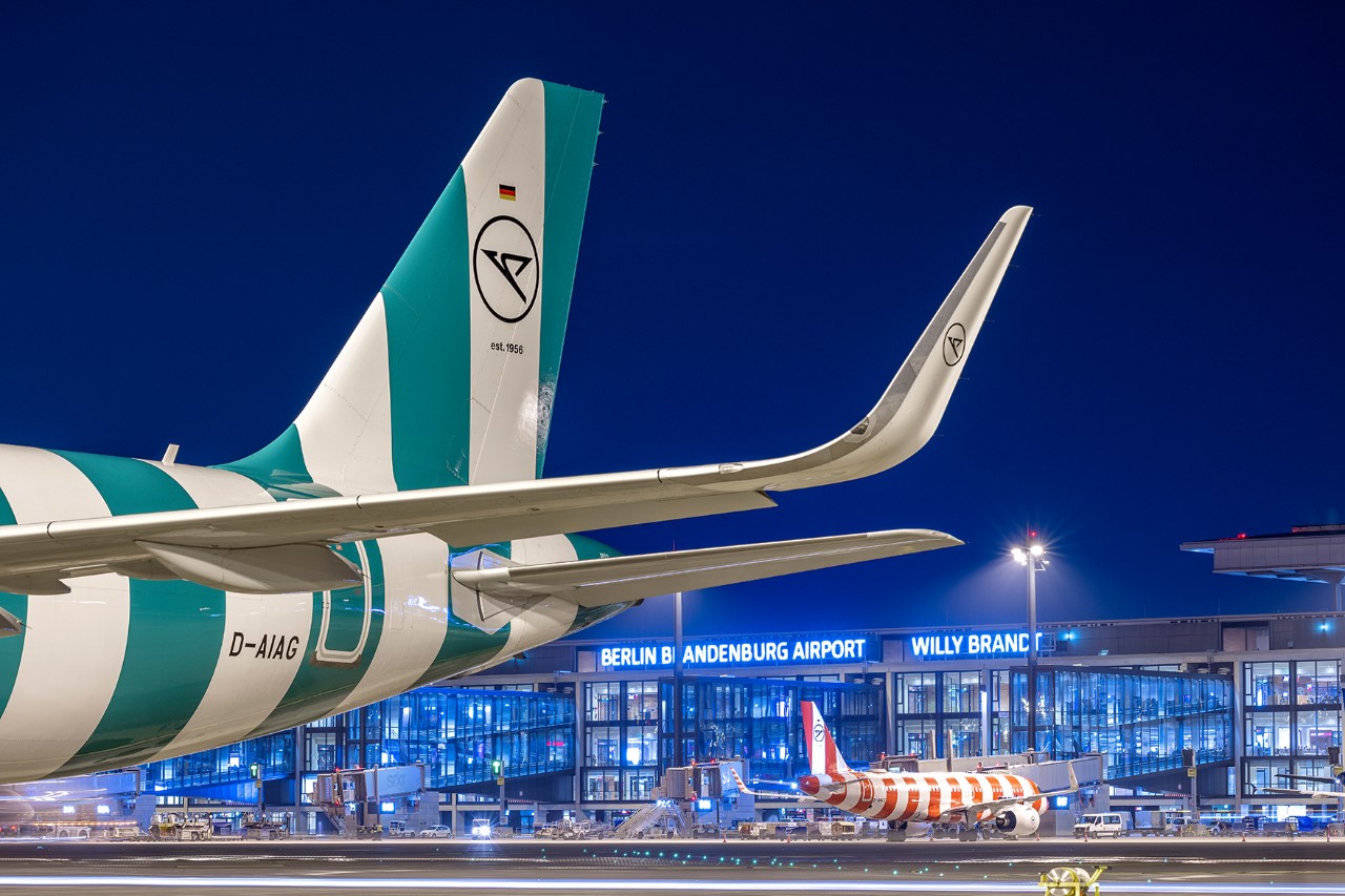 A Condor airline plane stands on the apron at night. 