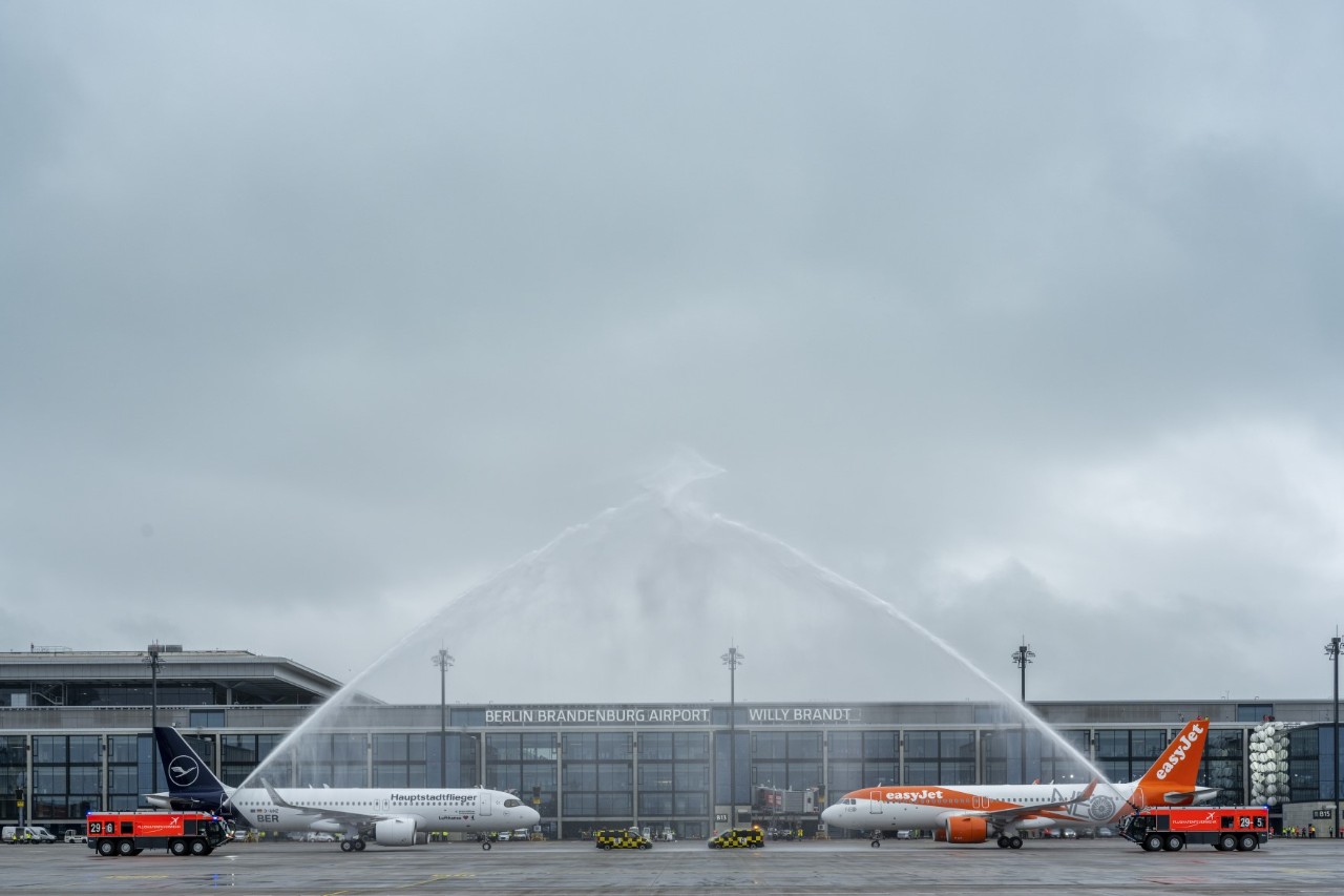 Two aircraft on the apron being sprayed with water by fire engines.