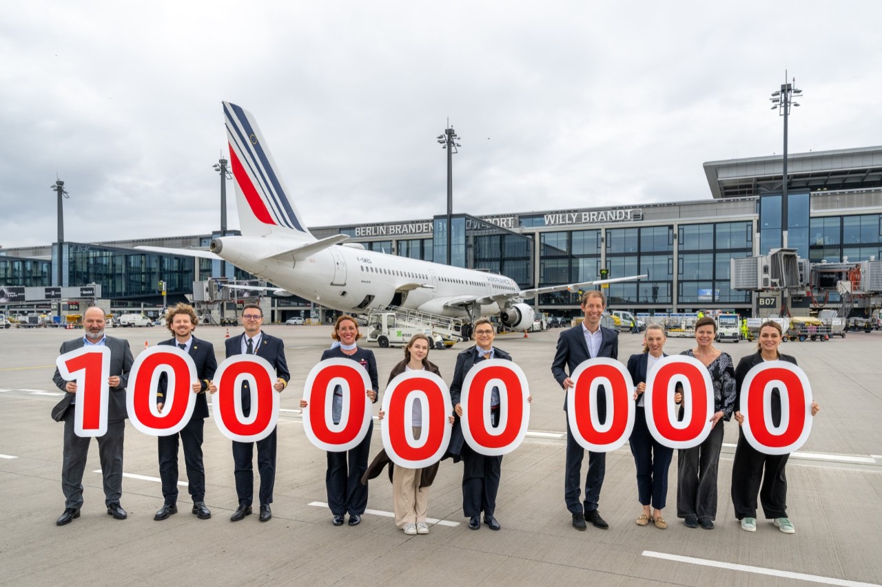 Group photo of several people holding signs that form the number one hundred million.
