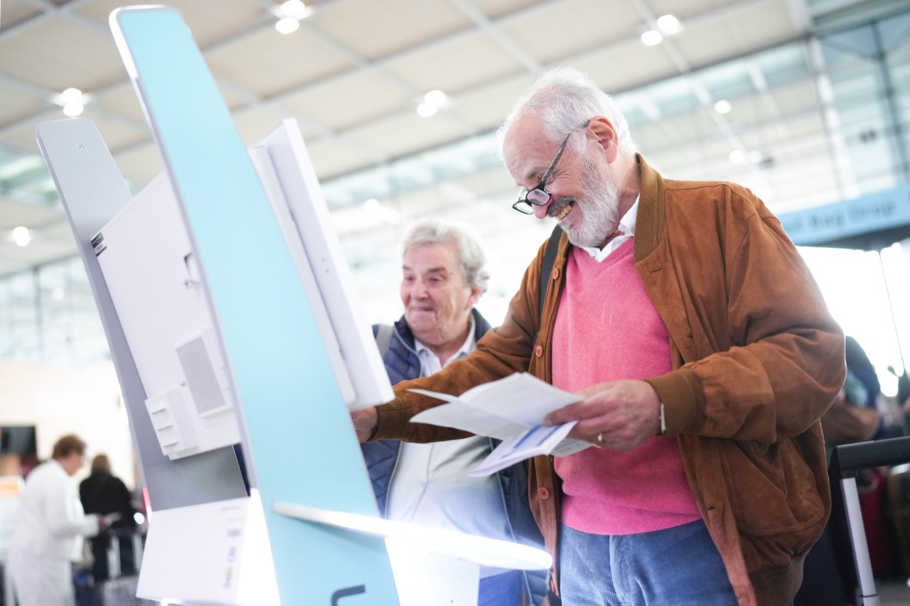 Two elderly people at a self-check-in machine