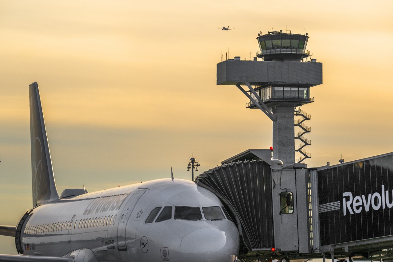 An aircraft at the gate. An airport control tower in the background.