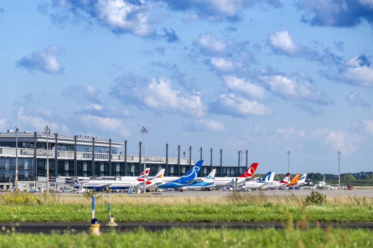 Many aircraft at an airport terminal.