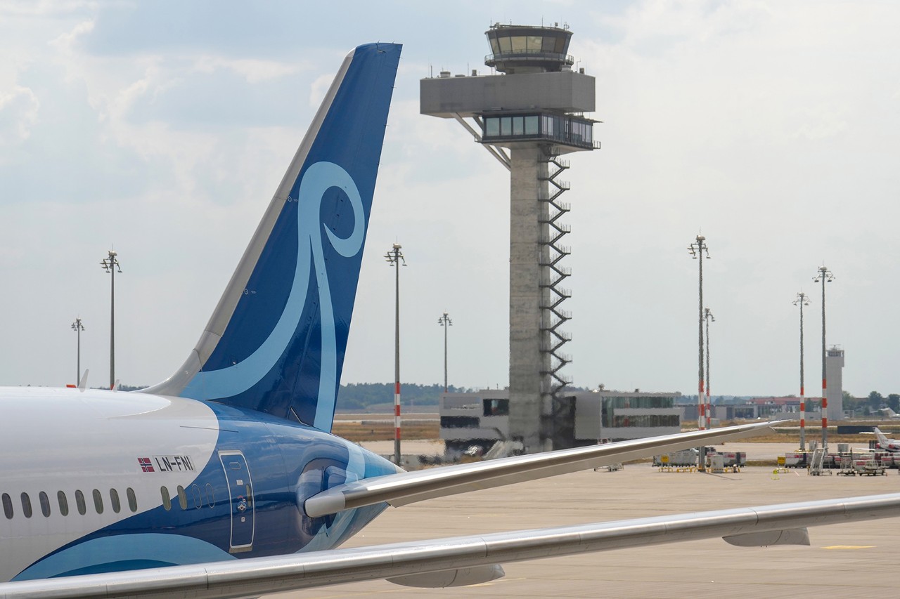 tbdBlick aus dem Gate auf die Boeing 787 mit der Kennung LN-FNI und dem Namen "Jontunheimen". Im Hintergrund das BER-Vorfeld und der 72 Meter hohe Tower der Deutschen Flugsicherung.