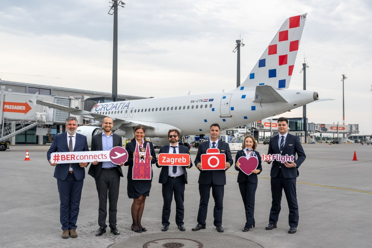 Seven people stand in front of a Croatia Airlines plane. They are holding up various signs to mark the airline's maiden flight from BER to Zagreb. © Günter Wicker / Flughafen Berlin Brandenburg GmbH