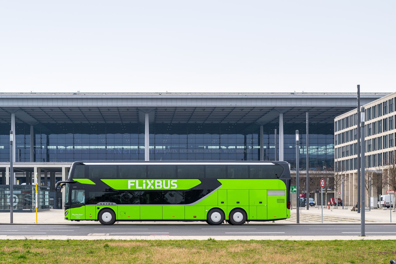 A green long-distance coach is parked in front of the terminal. The long-distance coach is shown from the side.