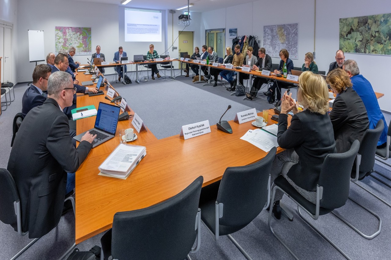 Many people are sitting around a large conference table.